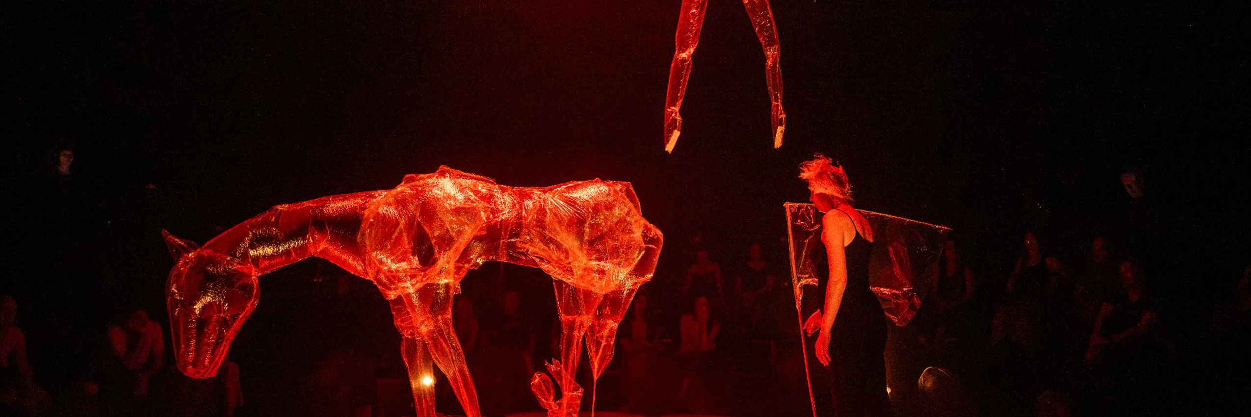 In glutrotes Licht getaucht schweben transparente Plastikfiguren über der Bühne von Nocturne Parade und erinnern an die düstere Welt von Goethes Erlkönig. © Sigrid Spinnox