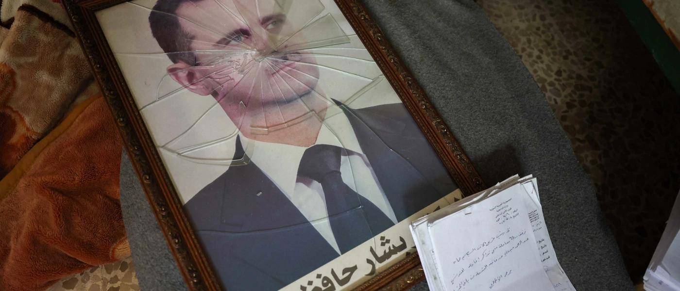 Ein Portrait des gestürzten syrischen Machthabers Bashar al-Assad hinter zerbrochenem Glas © OMAR HAJ KADOUR / AFP / picturedesk.com