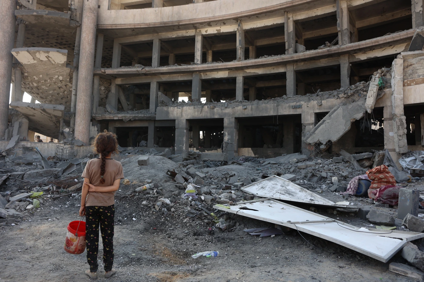Ein palästinensisches Mädchen steht nach einem nächtlichen Angriff vor dem zerstörten Sheikh-Radwan-Gesundheitszentrum im Norden von Gaza-Stadt, 6. August 2025. © OMAR AL-QATTAA/AFP via Getty Images