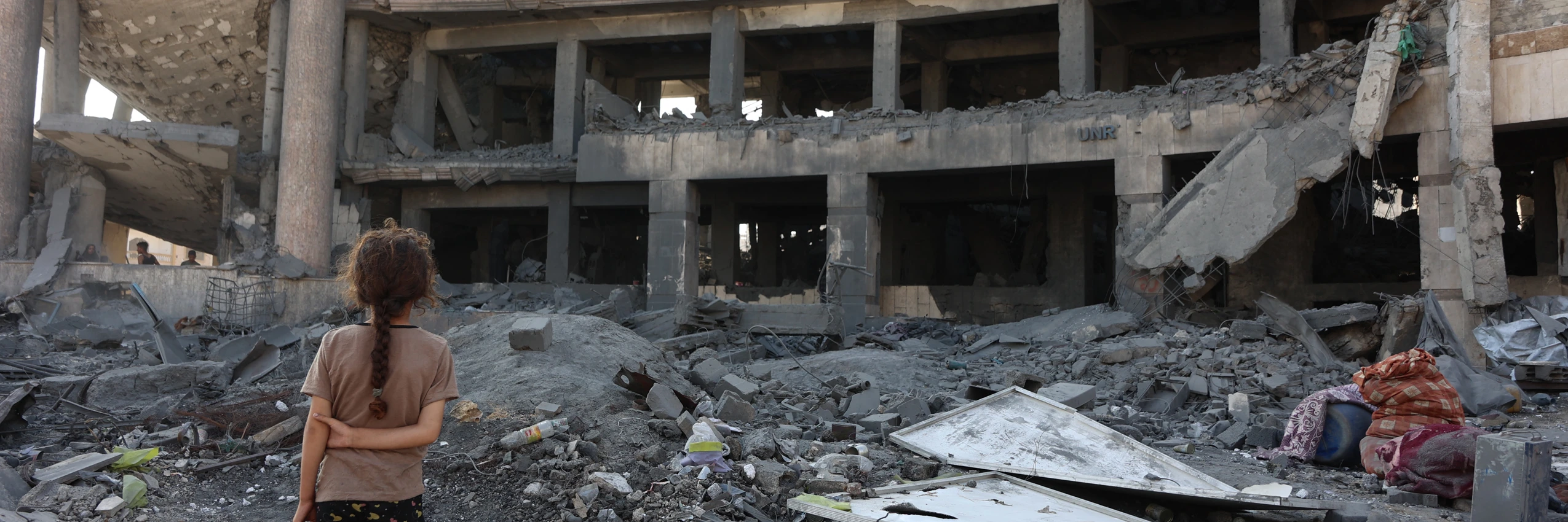 Ein palästinensisches Mädchen steht nach einem nächtlichen Angriff vor dem zerstörten Sheikh-Radwan-Gesundheitszentrum im Norden von Gaza-Stadt, 6. August 2025. © OMAR AL-QATTAA/AFP via Getty Images