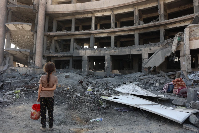 Ein palästinensisches Mädchen steht nach einem nächtlichen Angriff vor dem zerstörten Sheikh-Radwan-Gesundheitszentrum im Norden von Gaza-Stadt, 6. August 2025. @ OMAR AL-QATTAA/AFP via Getty Images