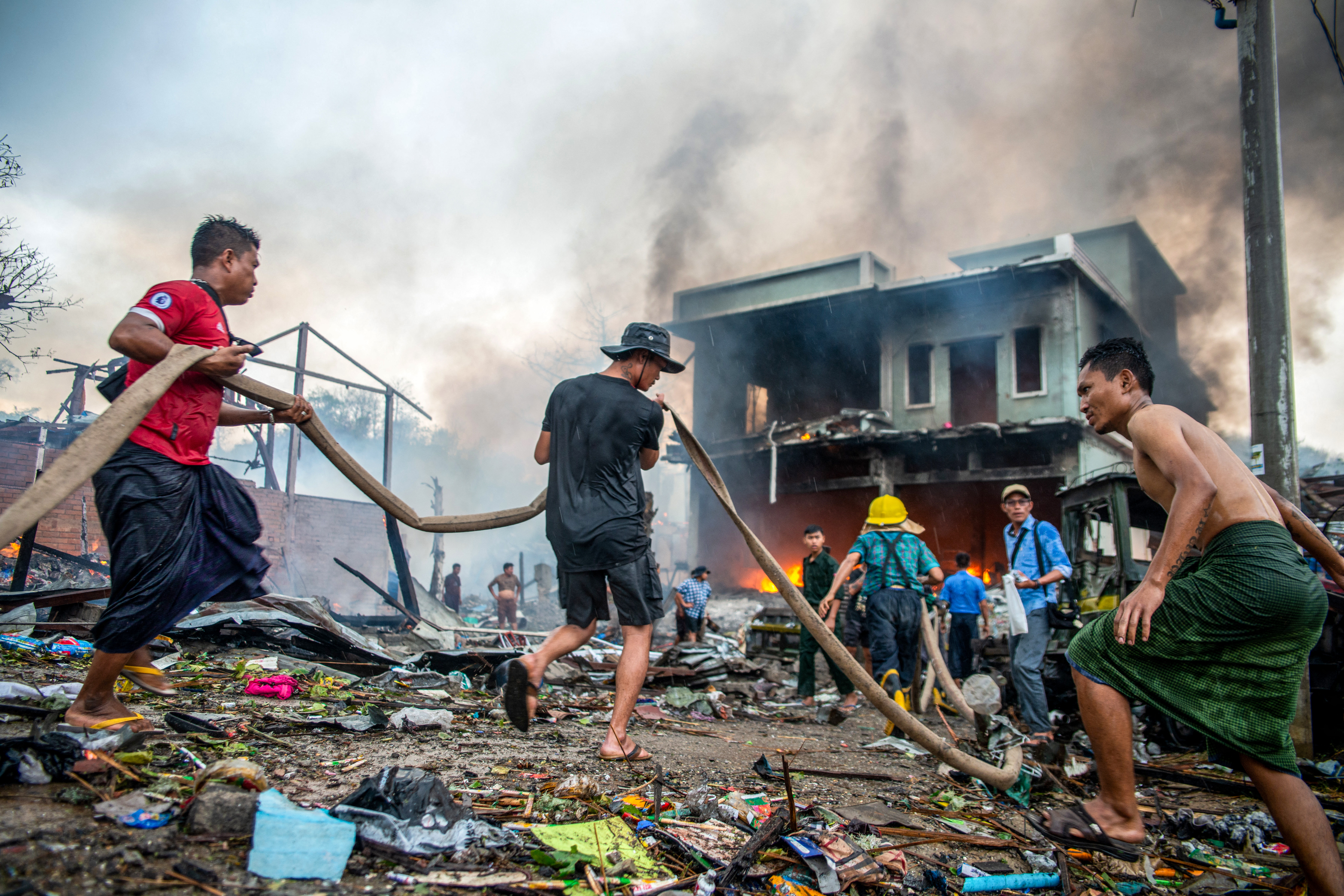 Menschen löschen einen Brand in einem zerstörten Gebäude in Thabeikkyin, Region Mandalay, 19. April 2025 – Myanmars Militär hat seit dem Putsch 2021 wiederholt zivile Infrastruktur angegriffen. © AFP via Getty Images