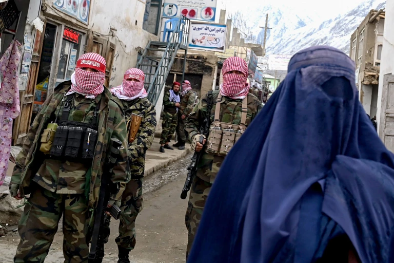 Bewaffnete Taliban hinter einer verhüllten Frau auf einem Markt im Bezirk Baharak in der Provinz Badakhshan, Afghanistan.  @ WAKIL KOHSAR / AFP / picturedesk.com