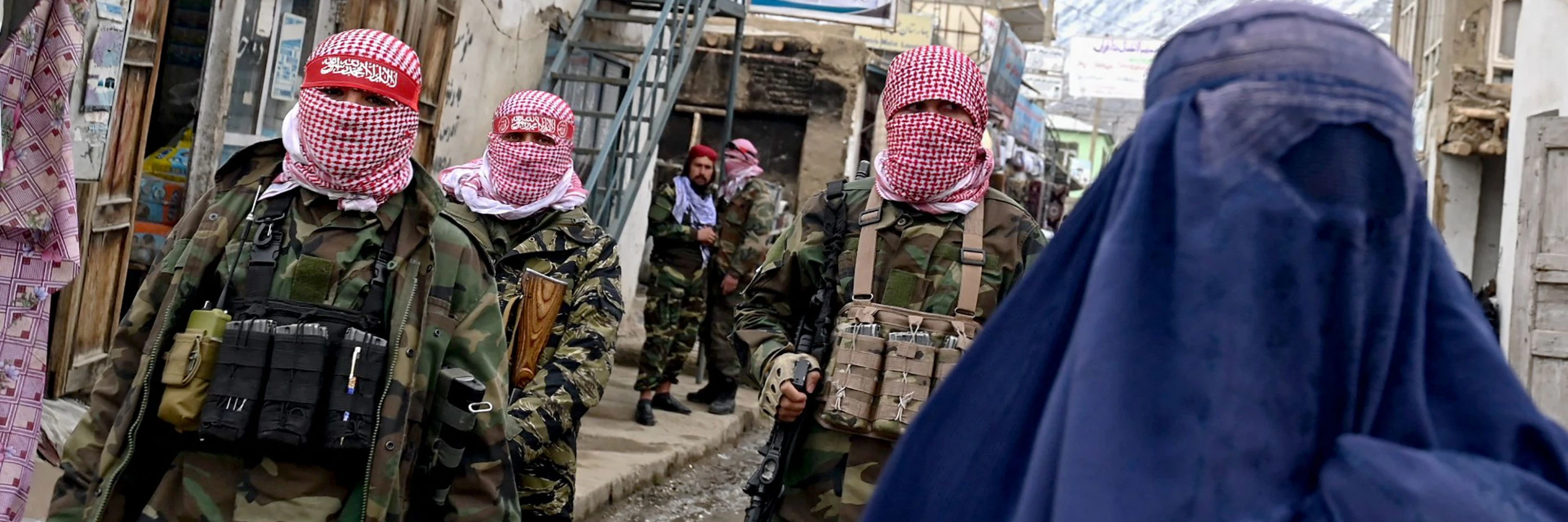 Bewaffnete Taliban hinter einer verhüllten Frau auf einem Markt im Bezirk Baharak in der Provinz Badakhshan, Afghanistan. © WAKIL KOHSAR / AFP / picturedesk.com