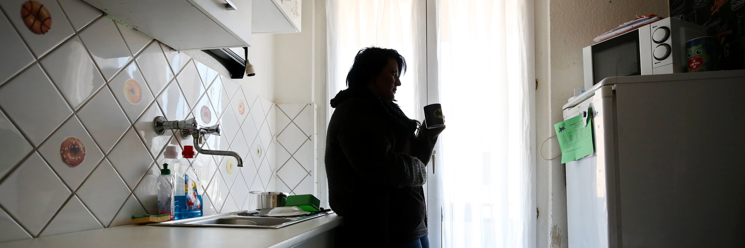 Eine Mutter steht in ihrer Küche. Wegen Stromsperre wurde der Familie im Winter Heizung und Warmwasser abgedreht. © Roland Weihrauch / dpa / picturedesk.com