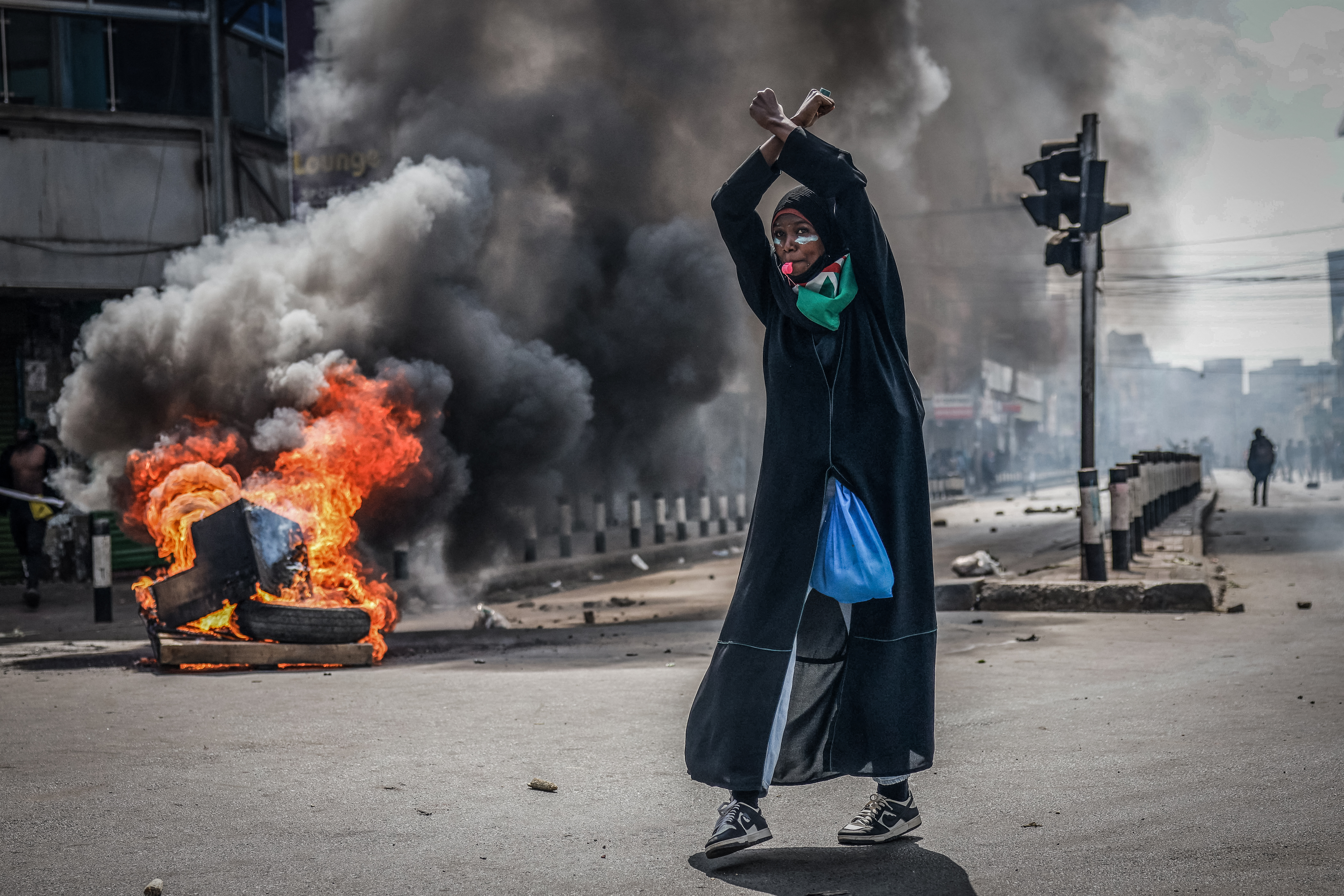 Eine Demonstrantin vor einer brennenden Barrikade, Nairobi, Kenia, 25. Juni 2025. Bei Protesten ein Jahr zuvor waren mindestens 60 Menschen von den Behörden getötet worden, Aufarbeitung fehlt. © Luis Tato / AFP via Getty Images
