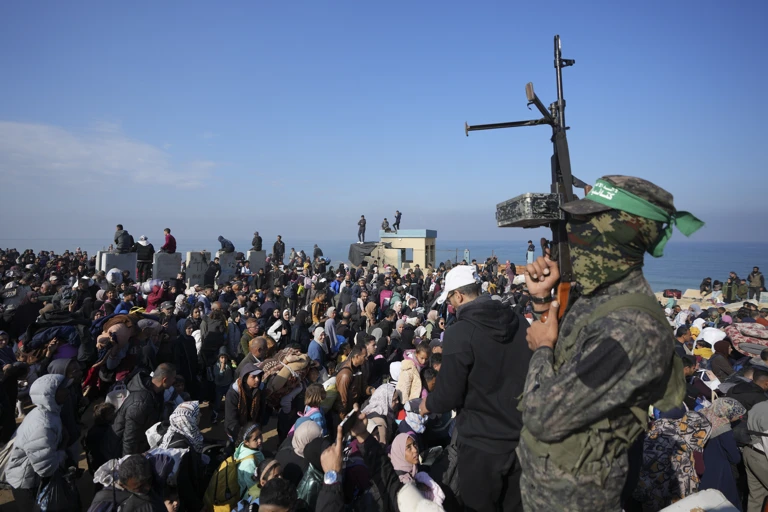 Ein Hamas-Kämpfer hebt seine Waffe, während vertriebene Palästinenser*innen in ihre Häuser im Gazastreifen zurückkehren (2025) @ APA-Images / AP / Abdel Kareem Hana