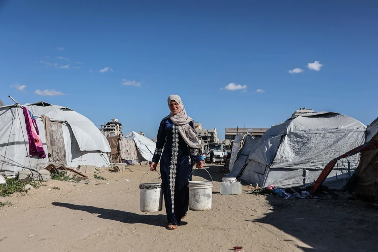 Eine vertriebene palästinensische Frau trägt in Gaza-Stadt Behälter mit Trinkwasser @ APA-Images / AFP / OMAR AL-QATTAA 