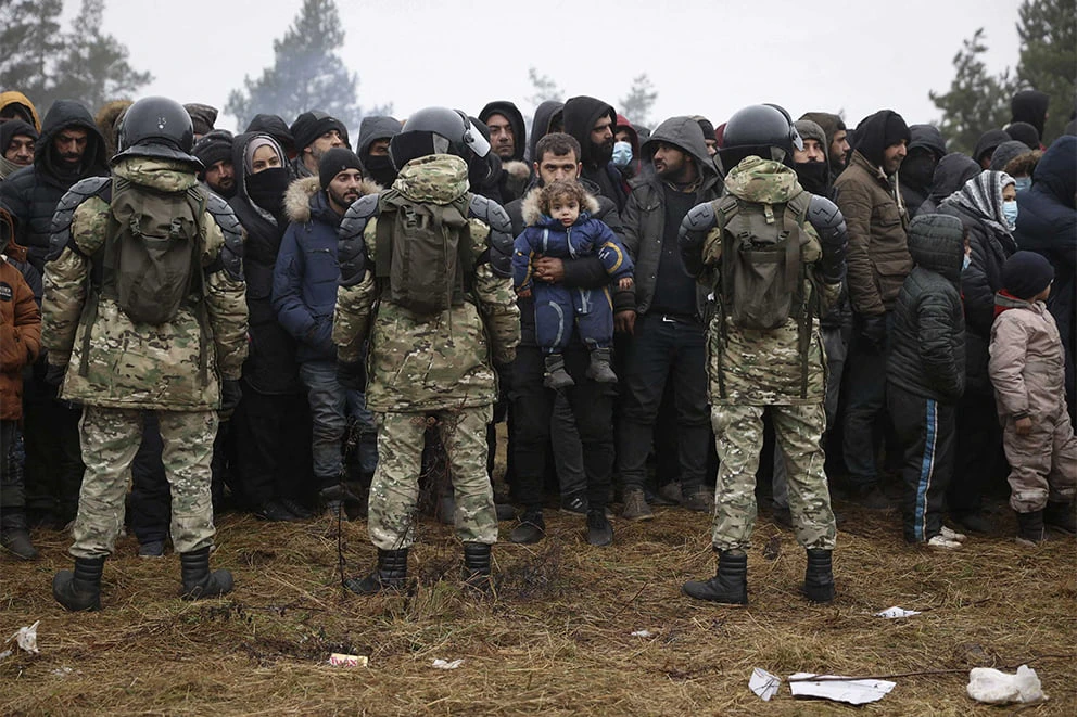 Migrant*innen stehen vor belarusischen Soldaten. Dutzende Migrant*innen wurden nach dem Überqueren der Grenze von Belarus nach Polen festgenommen. © BELTA / AFP via Getty Images