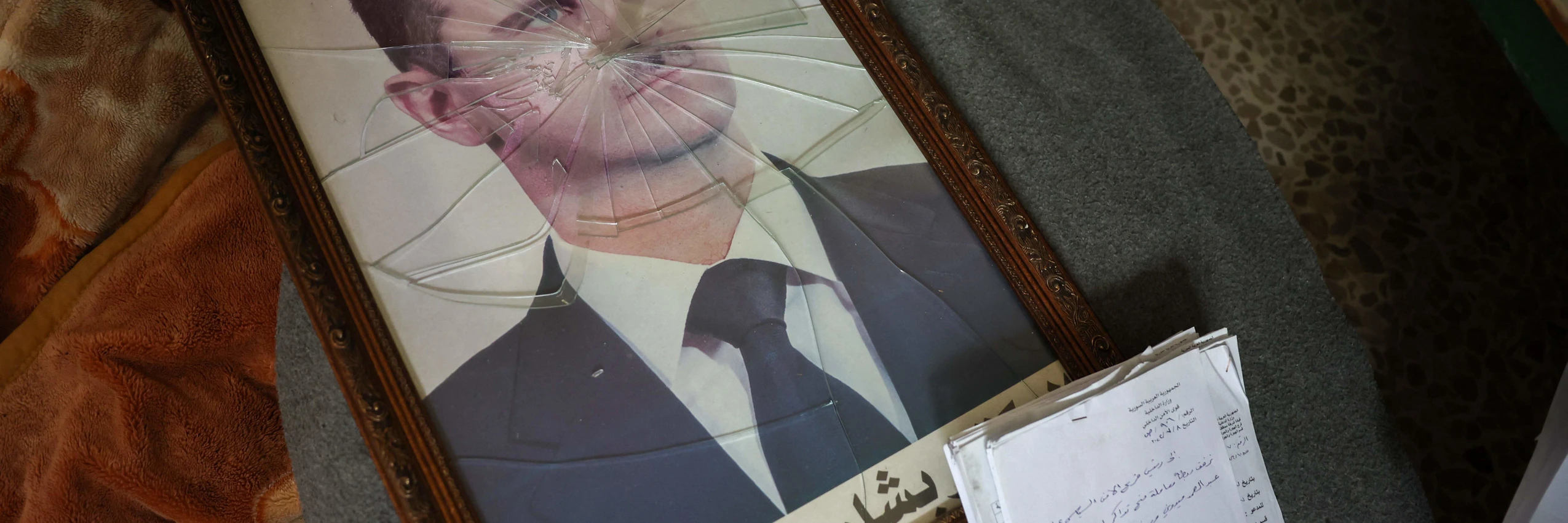 Ein Portrait des gestürzten syrischen Machthabers Bashar al-Assad hinter zerbrochenem Glas © Omar Haj Kadour / APA-Images