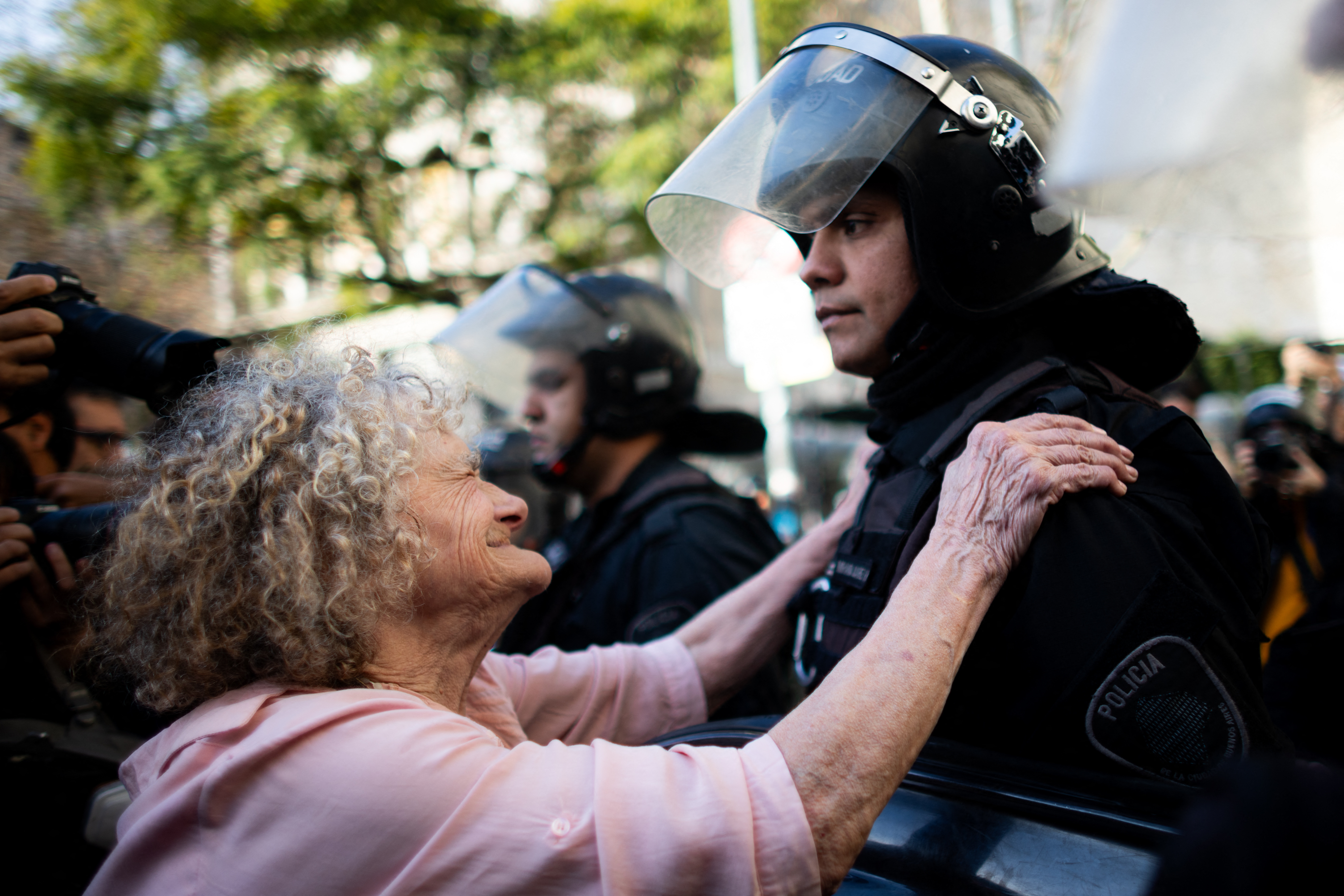 Eine Rentnerin versucht einen Polizisten zu umarmen, während Pensionist*innen vor dem Nationalkongress in Buenos Aires gegen Präsiden Mileis sozialen Kürzungen protestieren, 30. Juli 2025. © TOMAS CUESTA/AFP via Getty Images